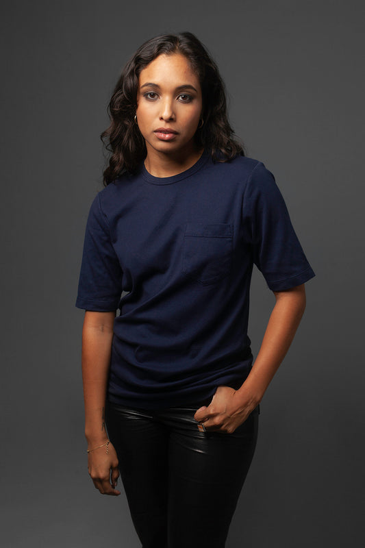 A person wearing a navy blue premium shirt made of Japanese cotton that is unisex with a pocket on their right breast.